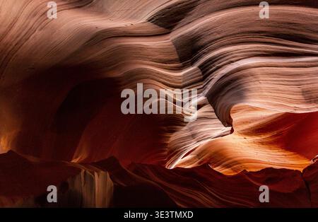 View of swirling sandstone walls, illuminated by soft light and casting deep shadows, creating a mesmerizing dance of color and texture, Page, Arizona Stock Photo