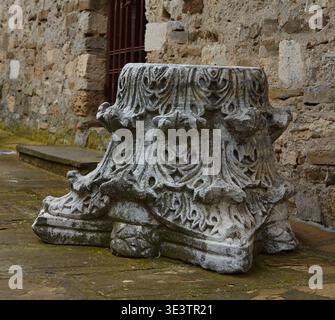 Nessebar, Bulgaria - March 22, 2026: Antique Byzantine column capital featuring detailed carvings positioned on stone pavement near a weathered wall i Stock Photo