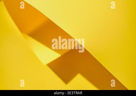 Yellow paper featuring curving lines creating abstract shapes and strong shadows Stock Photo