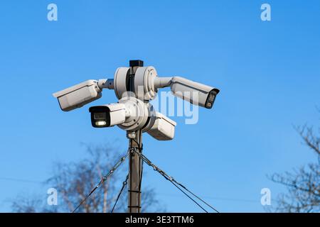 Cluster of security surveillance cameras mounted on a pole, pointing in multiple directions for monitoring and safety outdoors Stock Photo
