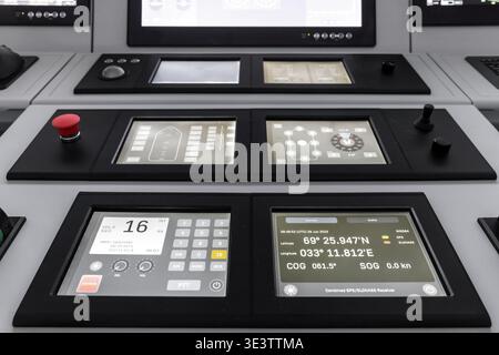 Modern ship bridge navigation control panel showing GPS coordinates, touchscreen displays and instrument readouts. Closeup of maritime control screens Stock Photo