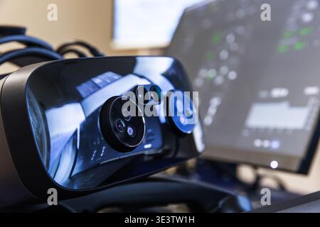 A modern virtual reality headset featuring multiple cameras and sensors, resting on a desk beside a blurred computer monitor, conveying immersive tech Stock Photo