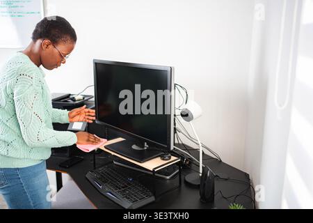Woman cleaning office desk computer monitor hygiene Stock Photo