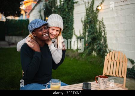 Happy diverse couple embracing at backyard table Stock Photo