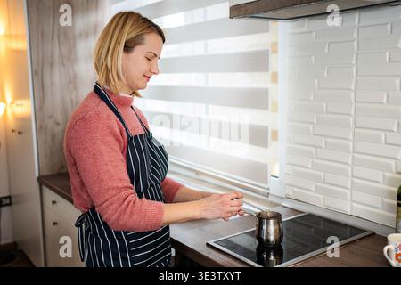 Woman making traditional Turkish coffee in kitchen Stock Photo