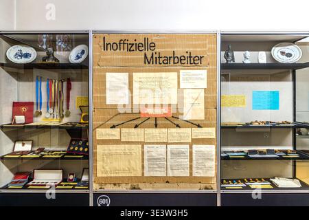 The “Unofficial Collaborators” exhibition area at the Museum in the Runden Ecke in Leipzig: display cases containing medals, identity cards and surveillance equipment used by the East German Stasi, as well as a display case illustrating the structure and recruitment methods of the Stasi’s network of informants. Leipzig, Saxony, Germany Stock Photo
