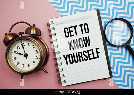 Get To Know Yourself text written on notepad with alarm clock and magnifying glass Stock Photo