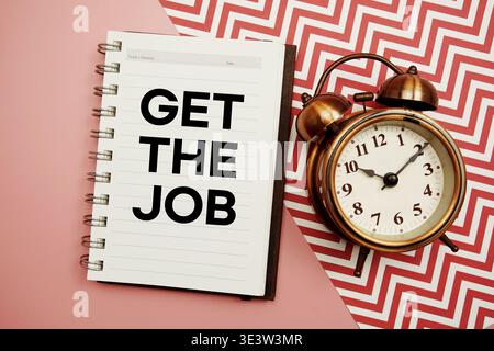 Get The Job text written on notepad with alarm clock Stock Photo