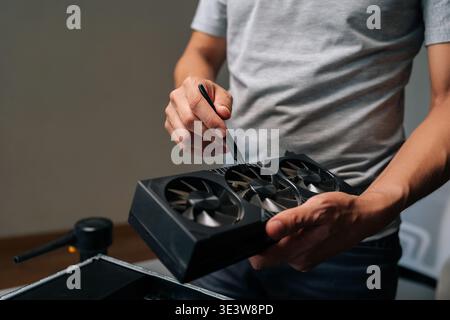 Closeup cropped shot of unrecognizable computer technician brushing graphics card, cleaning delicate electronic component for maintaining peak Stock Photo