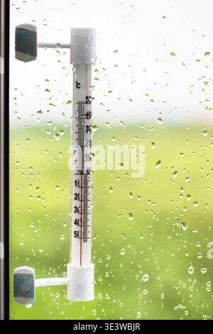 Window glass with raindrops and thermometer on summer day Stock Photo