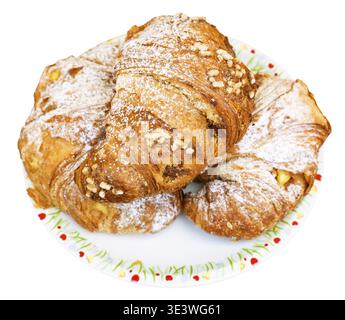Three fresh Italian croissants filled with vanilla and chocolate on a plate, against a white background Stock Photo