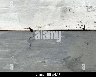 Fresh concrete being poured over a reinforced steel mesh on a construction site. The wet concrete seamlessly blends into the surrounding area, showcas Stock Photo