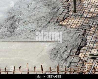 A construction site with concrete being poured over a steel mesh framework. This setup is essential for building strong foundations and ensures struct Stock Photo