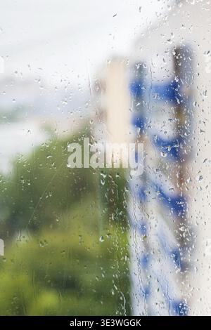 Raindrops on the window and blurred houses in the background Stock Photo