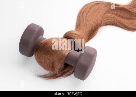 A unique concept image depicting strong, silky hair intertwined with a weight, symbolizing the strength and vitality achieved through hair cosmetics a Stock Photo