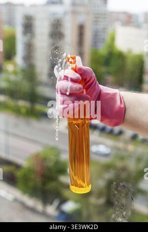 Wash house windows â€” Liquid from the spray bottle is sprayed onto the window glass in an apartment building by hand Stock Photo
