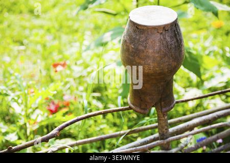 Rural landscape of old clay pot in close-up at the willow fence Stock Photo
