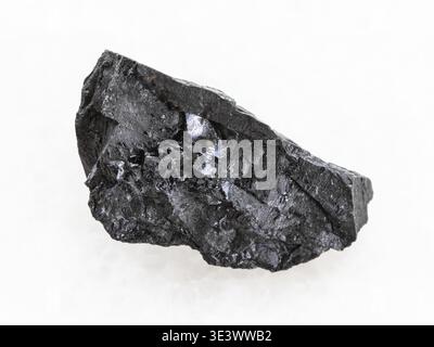 Macro shot of a natural rock sample of rough anthracite charcoal on white marble background Stock Photo