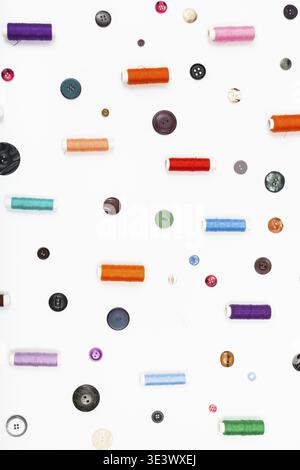 Lots of spools of thread and various buttons on white background Stock Photo