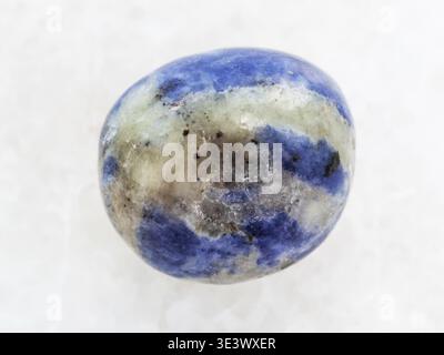 Macro shot of a natural rock sample of polished sodalite gemstone on white marble background Stock Photo