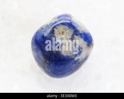 Macro shot of a natural rock sample of polished sodalite gemstone on white marble background Stock Photo