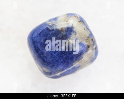 Macro shot of a natural rock sample tumbled sodalite gemstone on white marble background Stock Photo