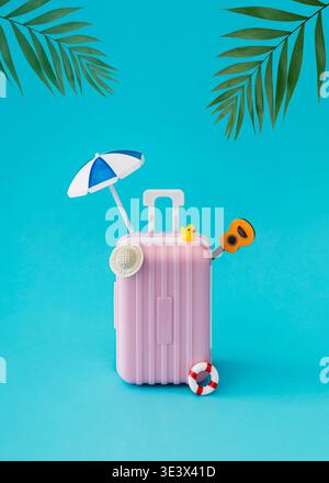 Summer travel composition with pink suitcase, beach umbrella, beach accessories and tropical palm leaves on light blue background. Stock Photo