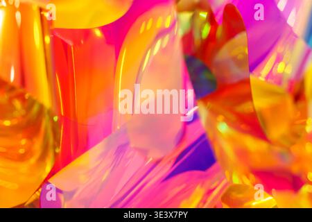 Bright iridescent holographic texture with vibrant pink, orange and yellow colors. Abstract background photography showing colorful light reflections, neon gradients and creative aesthetic ripples. High quality photo Stock Photo