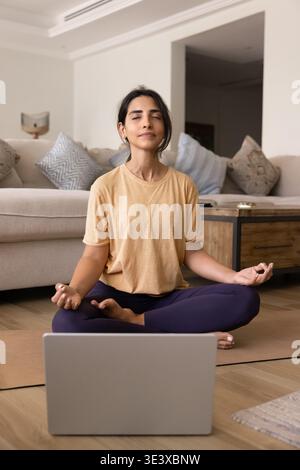 Woman practicing meditation or breathing exercises in front of laptop Stock Photo