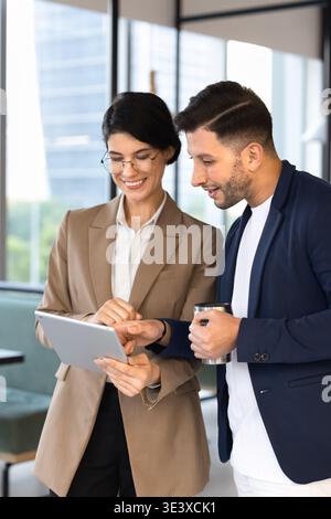 Two smiling colleagues discussing new business application on digital tablet Stock Photo