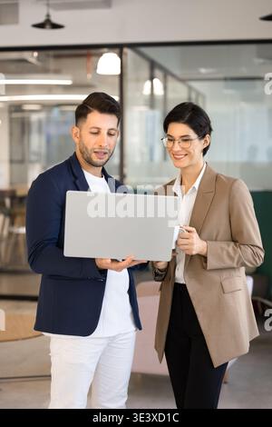 Multiethnic team collaborate on project standing in office with laptop Stock Photo