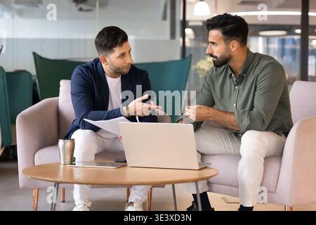 Two male colleagues collaborate on task in office lounge Stock Photo