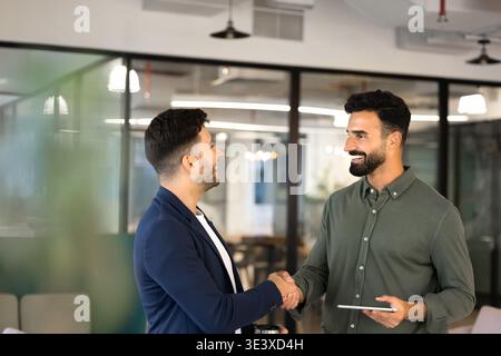Businessmen shaking hands completing successful partnership deal in office Stock Photo