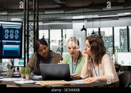 Multiethnic goals oriented team of women demonstrating the power of leadership, collaborating on boardroom planning with data analytics and monthly reports. Modern work environment. Stock Photo