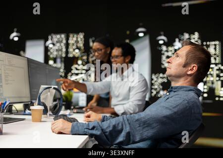 Silicon Valley startup office software developer relaxing at desk, letting AI assistant do tasks. Technician daydreaming at work while high tech artificial intelligence LLM models does his job Stock Photo
