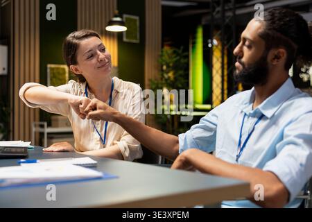 Doing fist bump, laptop and cheerful office coworkers pleased by business results after analyzing data. Celebrating positive financial figures, notebook and jolly Arab man and colleague in workplace Stock Photo