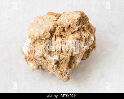 Macro shot of a natural rock sample of rough travertine stone on white marble background Stock Photo