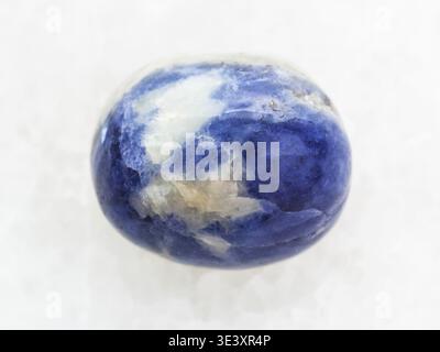 Macro shot of a natural rock sample tumbled sodalite gemstone on white marble background Stock Photo