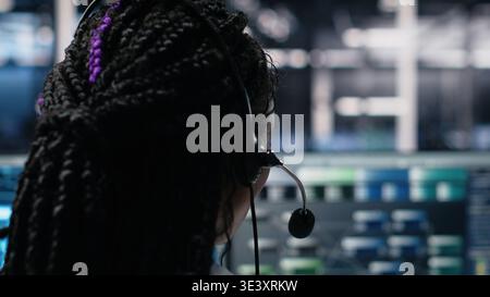 Data center admin using AI assistant to provide user technical support and solutions to users. Server farm IT expert managing live support calls assisted by artificial intelligence chatbot, camera A Stock Photo