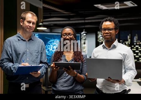 Portrait of happy teamworking programmers utilizing AI to optimize performance and forecast issues. Joyous coworkers in tech startup office training machine learning models Stock Photo
