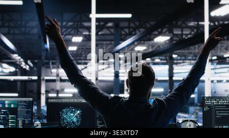 Delighted developer celebrating in data center after successfully coding with generative AI. Overjoyed employee doing high five with colleague after leveraging AI large language model, camera A Stock Photo