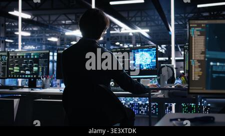 Admin in server room drinks coffee while using AI to review infrastructure diagnostics. IT specialist enjoys beverage in data center while analyzing performance with artificial intelligence, camera A Stock Photo