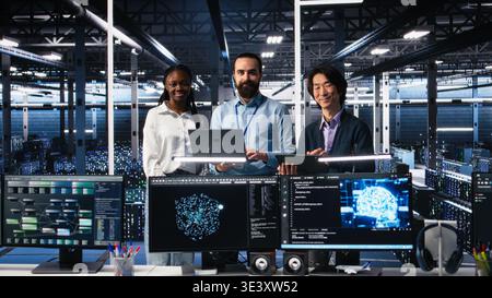 Portrait of smiling engineers in data center code with generative AI assistance. Happy IT experts doing brainstorming, leveraging artificial intelligence large language model to solve tasks, camera A Stock Photo