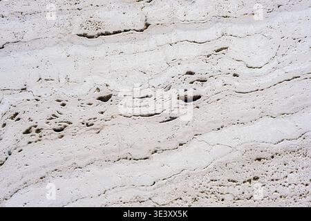 White travertine stone texture with natural porous pattern and cracks, abstract mineral background. Stock Photo