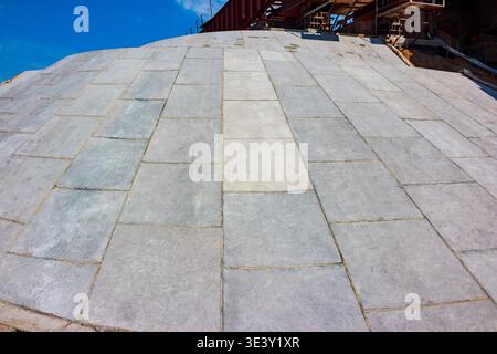 Wide-angle view of rugged concrete slab paving on a steep incline under a bright blue sky. Emphasizing solid construction and robust foundation work Stock Photo