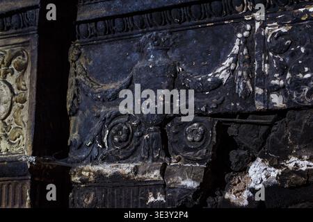 Aged, charred fireplace detail in derelict manor. Ornate stone, intricate carvings, soot. Captures ruin, forgotten history, and silent decay Stock Photo