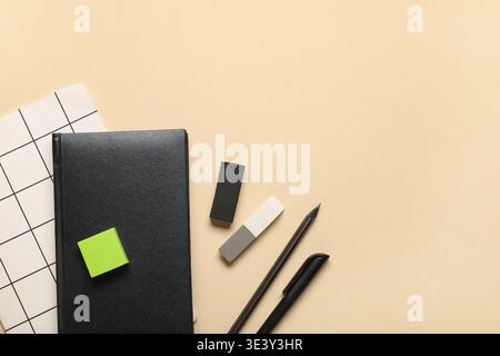 Different rubber erasers with notebooks, pencil and pen on beige background Stock Photo