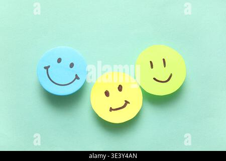 Sticky notes with smiley faces on turquoise background Stock Photo