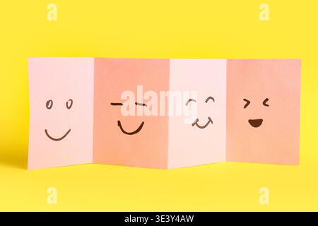 Sticky paper with drawn happy faces on yellow background Stock Photo