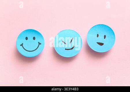 Sticky notes with smiley faces on pink background Stock Photo